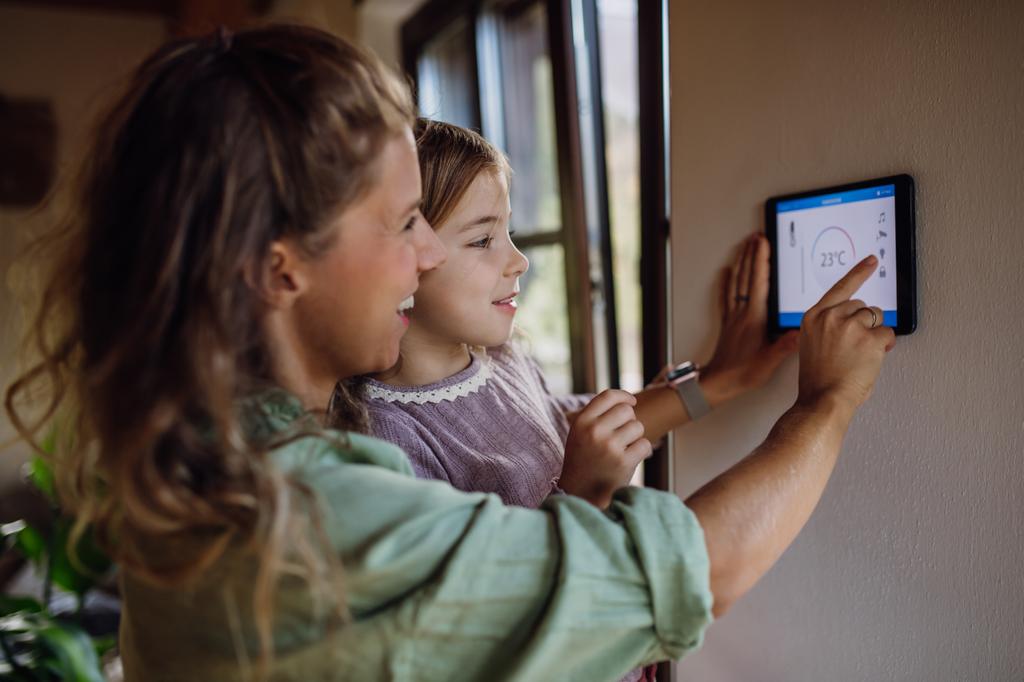 a little girl helping her mother adjust the thermostat